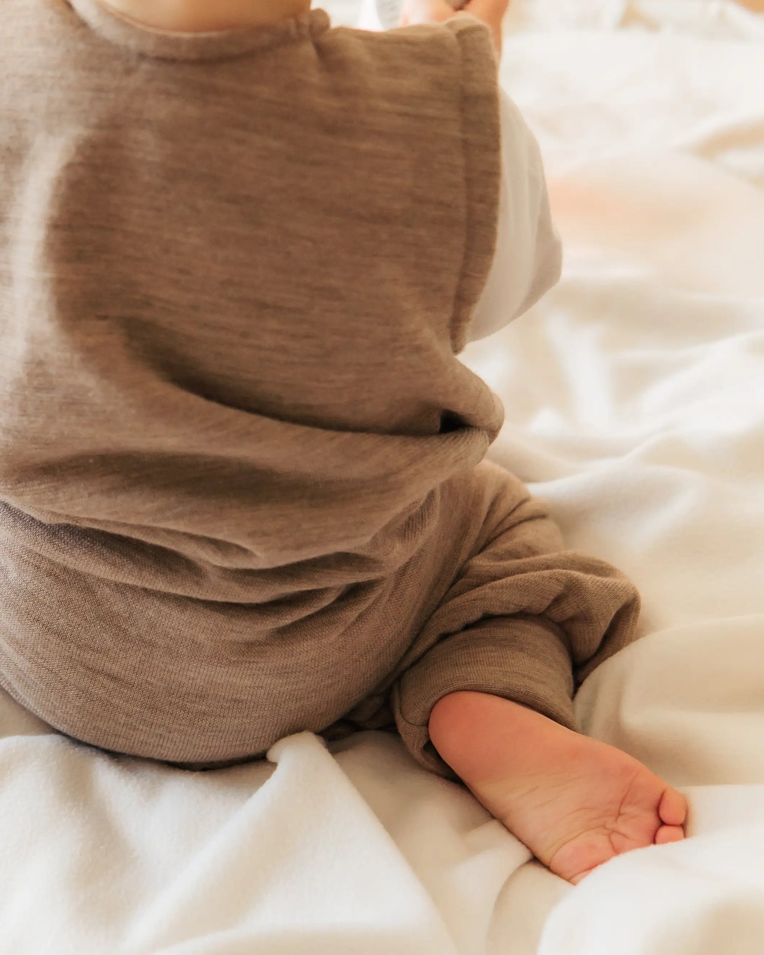 Kleinkind im Sommerschlafsack mit Beinen aus Merinowolle beim Laufen im Schlafzimmer, bewegungsfreundlich und temperaturregulierend