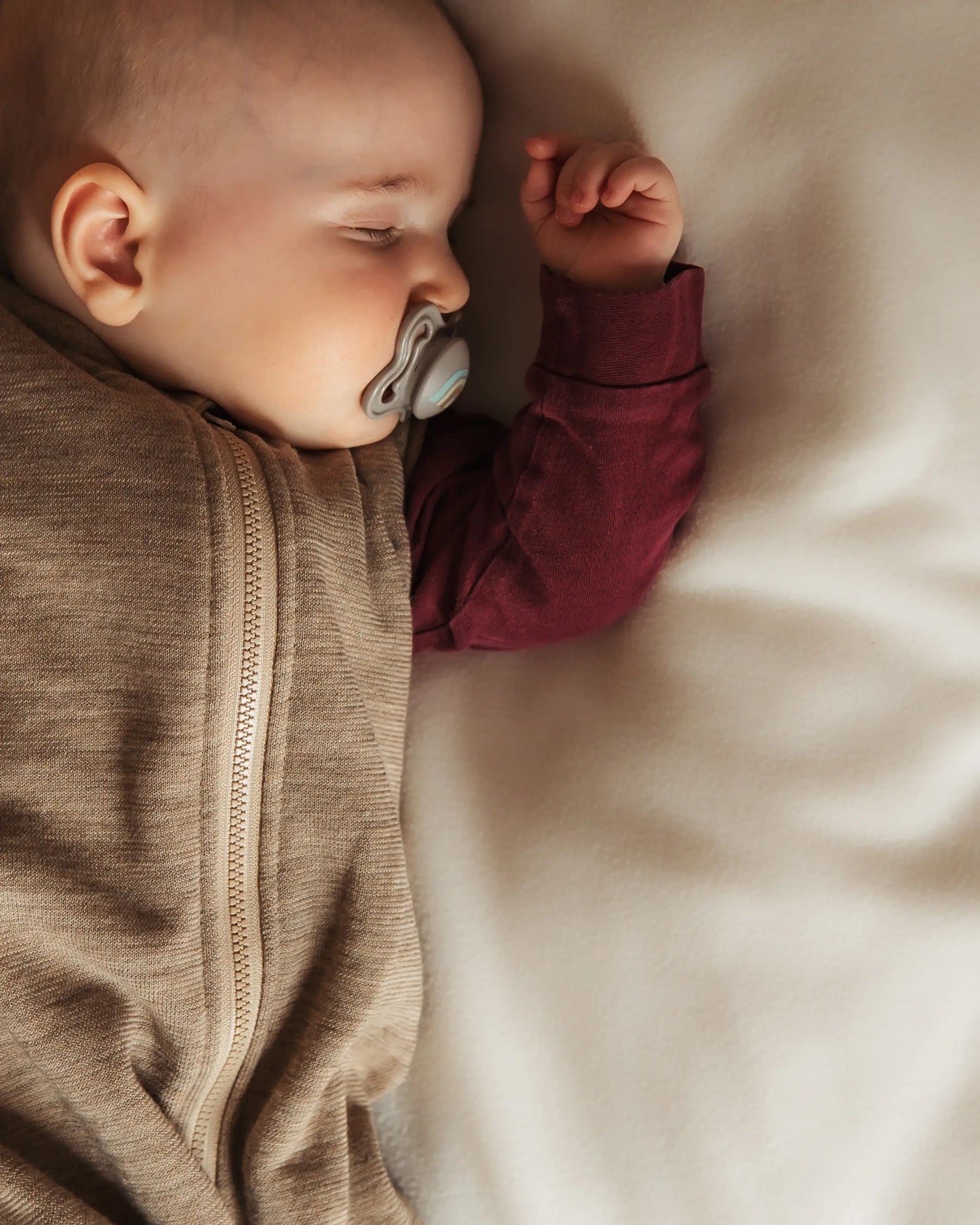 Neugeborenes Baby im weichen Merino Sommerschlafsack ohne Ärmel, gemütlich schlafend in natürlichem Wollfrottee für optimalen Temperaturausgleich
