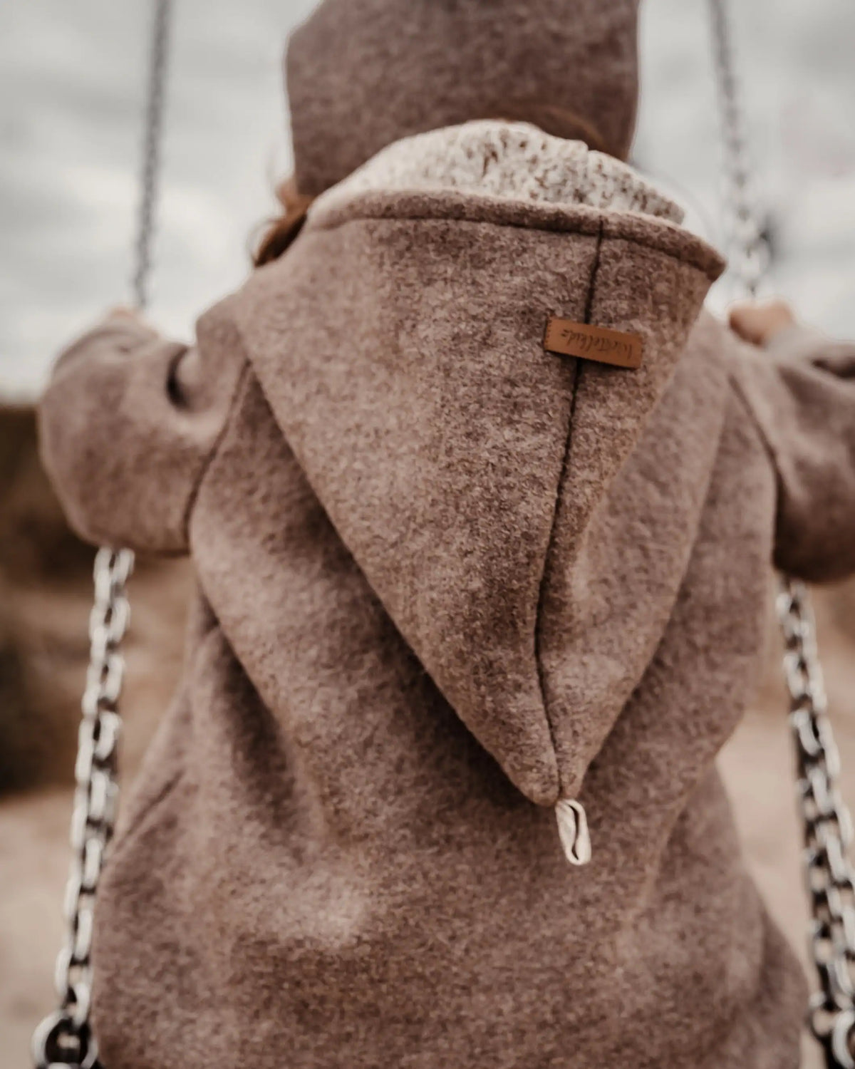 Kind mit Wichtelkidz Wollwalk Overall mit Zwergenkapuze beim Spielen im Freien – ideal für Kita und Spielplatz