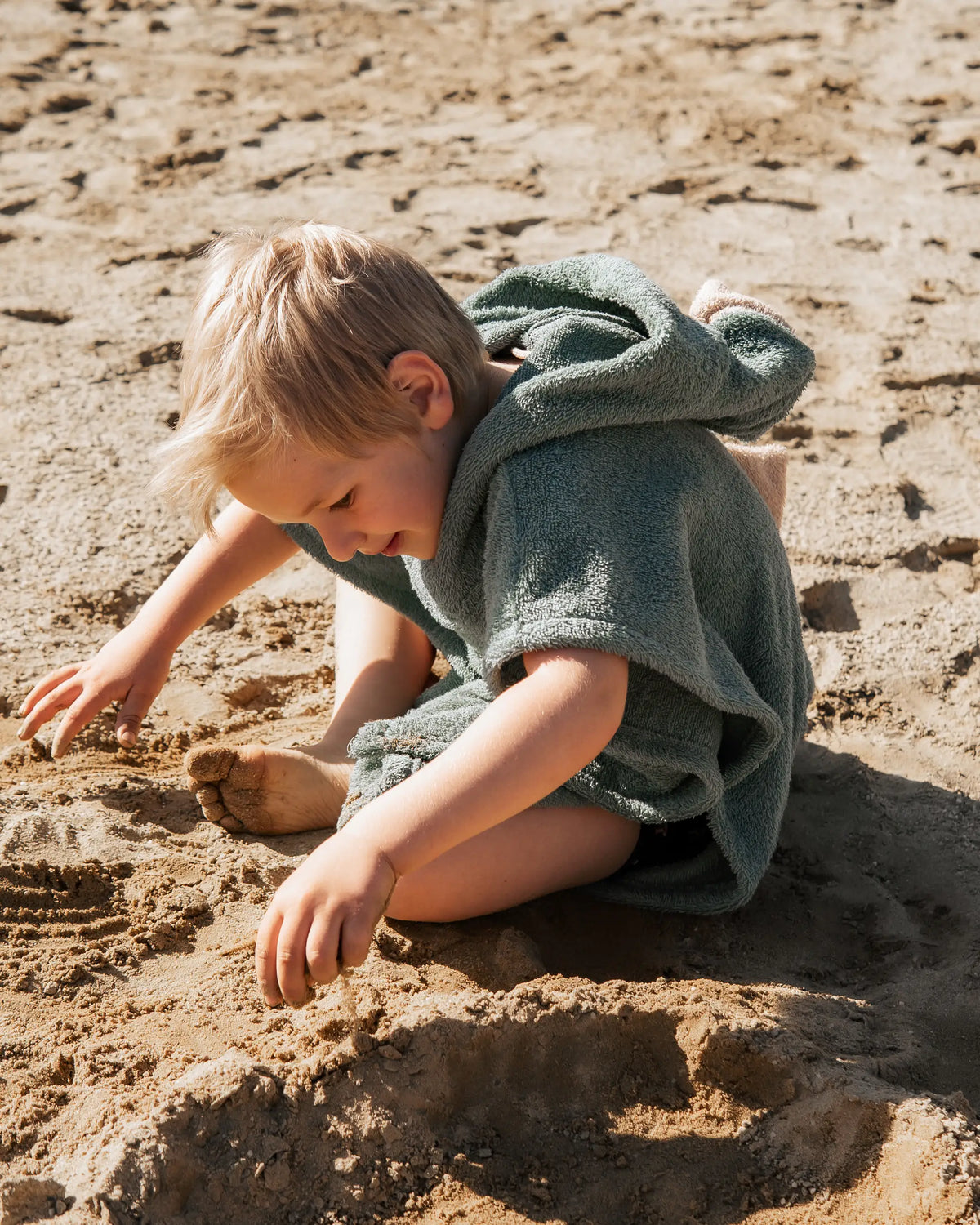 Weicher Kinder-Strandponcho Dino aus saugfähigem Baumwoll-Frottee mit Kapuze, Dinozacken und Bauchtasche – ideal für Bad, Pool oder Urlaub am Meer.
