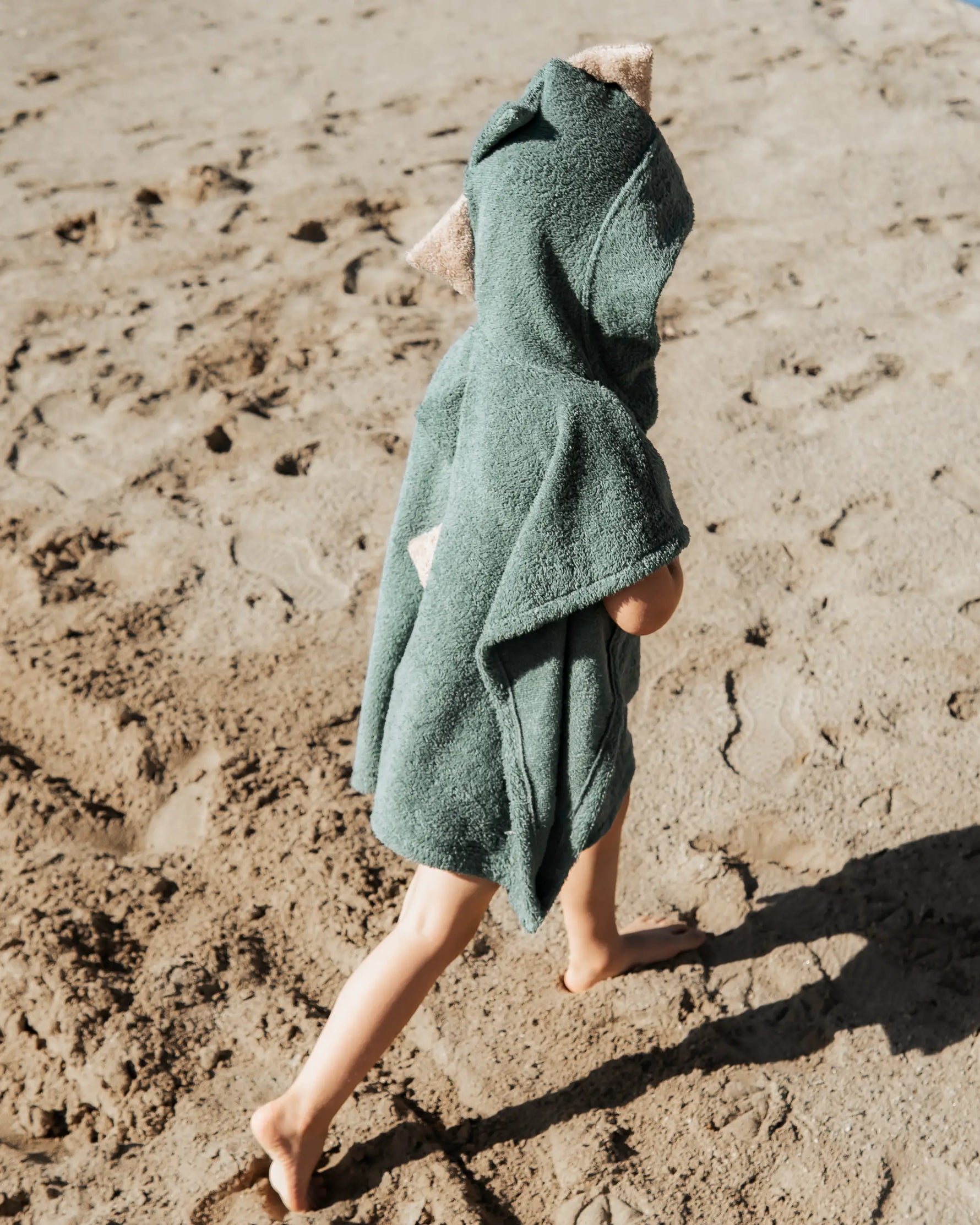 Weicher Kinder-Strandponcho im Dino-Design aus saugfähigem Baumwoll-Frottee mit Kapuze, Dinozacken und Bauchtasche – ideal für Bad, Pool oder Urlaub am Meer.