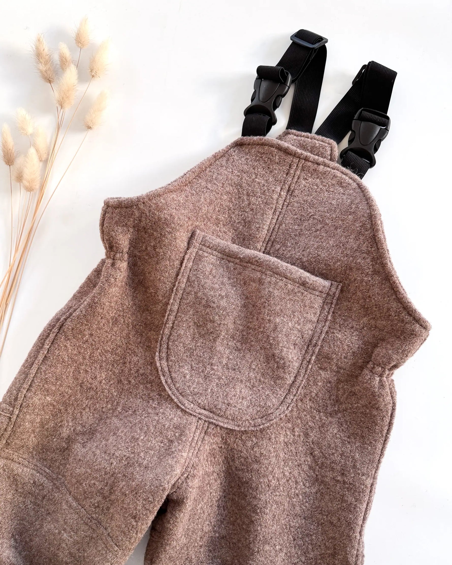 Detailaufnahme von Walklatzhose mit verstellbaren Trägern und Tasche, handgemachte Kinderkleidung aus Bio Materialien