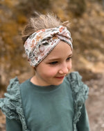 Mädchen in der Natur mit Stirnband mit Twist in tollen floralen Mustern. Perfekt für Frühling, Herbst und WInter