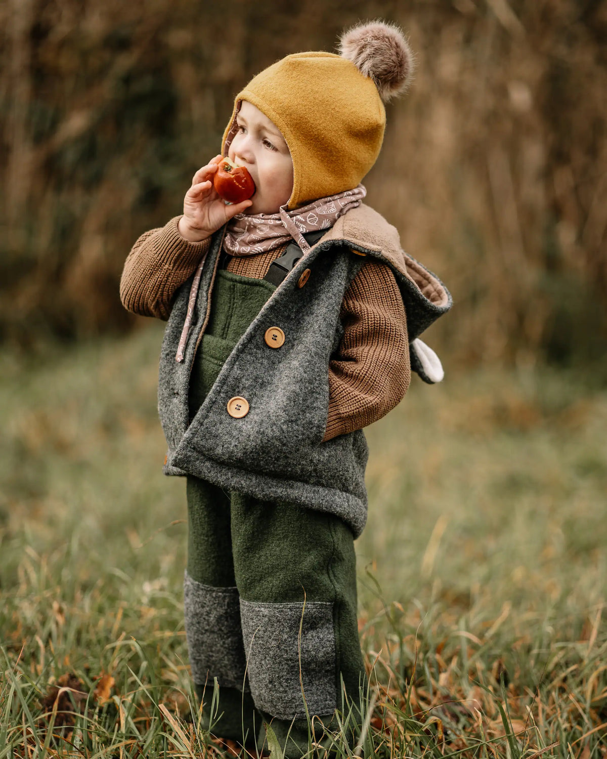 Kind trägt Walkweste mit Holzknöpfen aus Wollwalk beim Spielen draußen, nachhaltige Kinderkleidung aus 100% Schurwolle für Frühling und Herbst