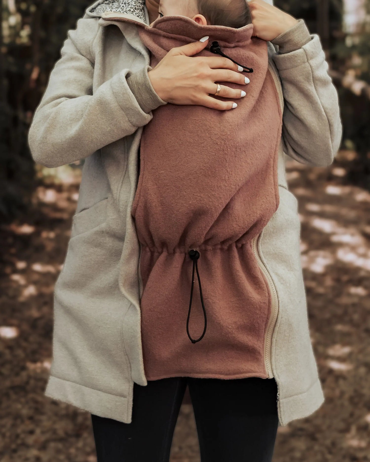 Mama trägt ihr Baby im Winter unter einer Jacke mit eingezipptem Trageeinsatz aus Wollwalk von Wichtelkidz