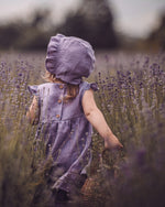 Kinder Stufenkleid / Leinenkleid für den Sommer mit passender Baby Bonnet in Lavendel. Individuell angefertigtes Kleid mit Rüschen, ideal für festliche Anlässe wie eine Taufe, Geburtstag, Hochzeit, als Kleid für ein Blumenmädchen oder die Einschulung.  Unsere Handgemachten Leinenkleider für Mädchen sind nachhaltig, regional und fair in Bayern angefertigt.
